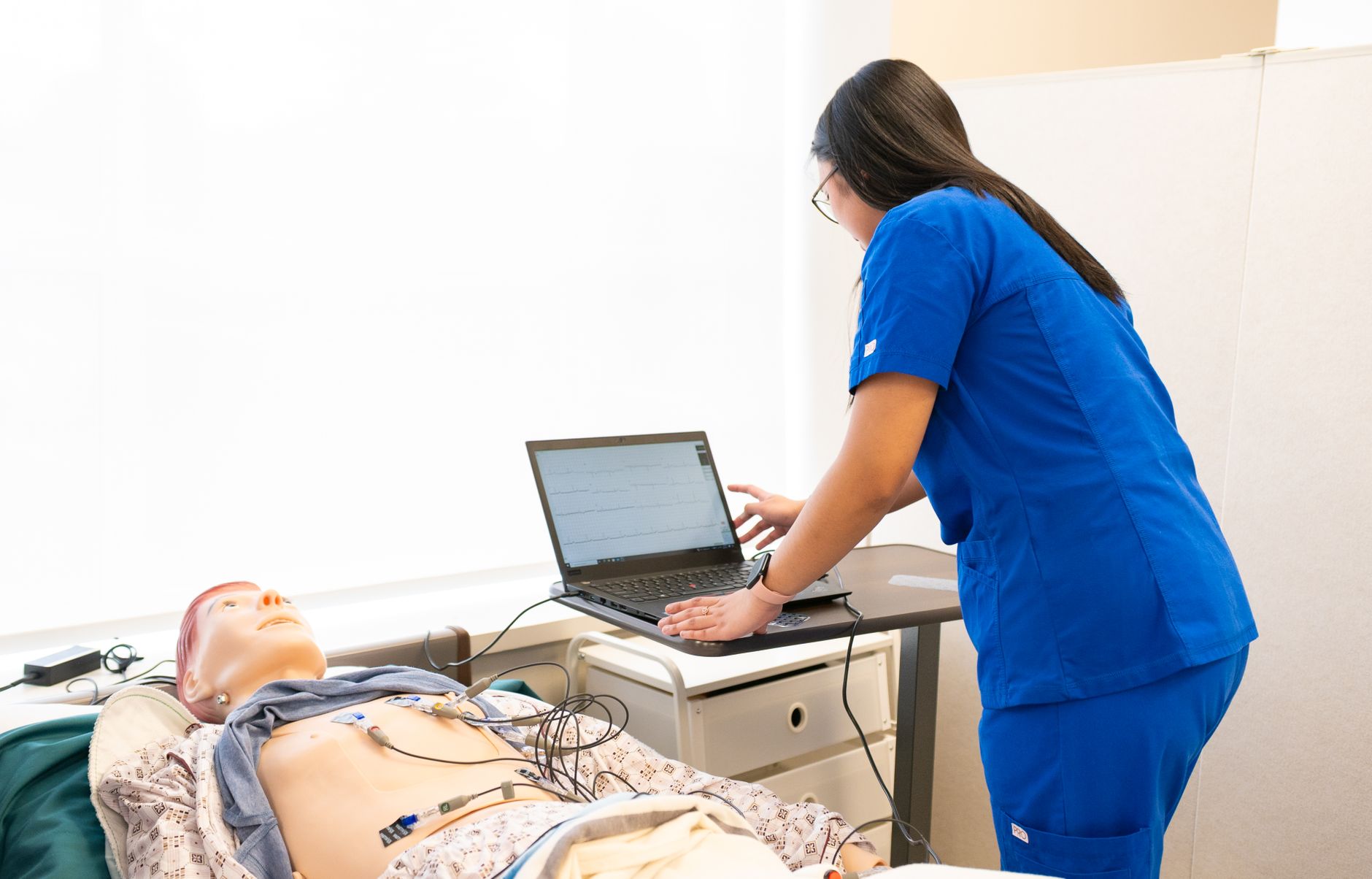 Nurse in training using a laptop with a medical dummy in a clinical simulation lab — UPI Study