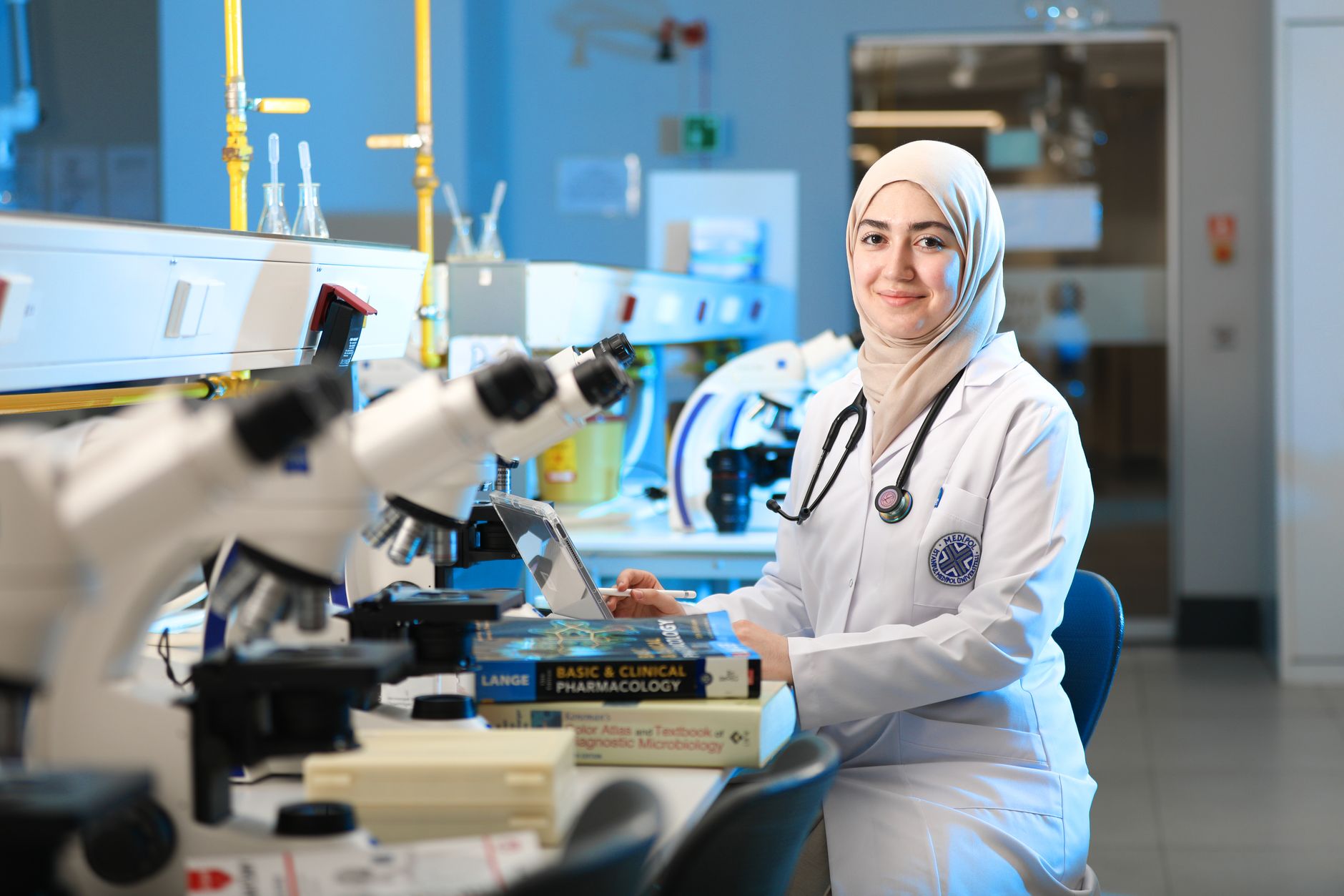 A female scientist in a laboratory setting, conducting research with microscopes and reference books — UPI Study