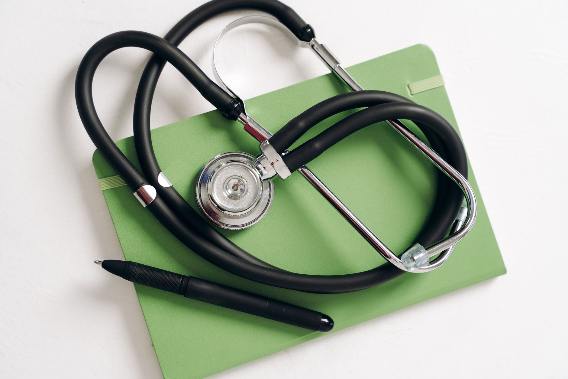 Top view of a stethoscope and pen on a green notepad, ideal for medical and educational themes — UPI Study