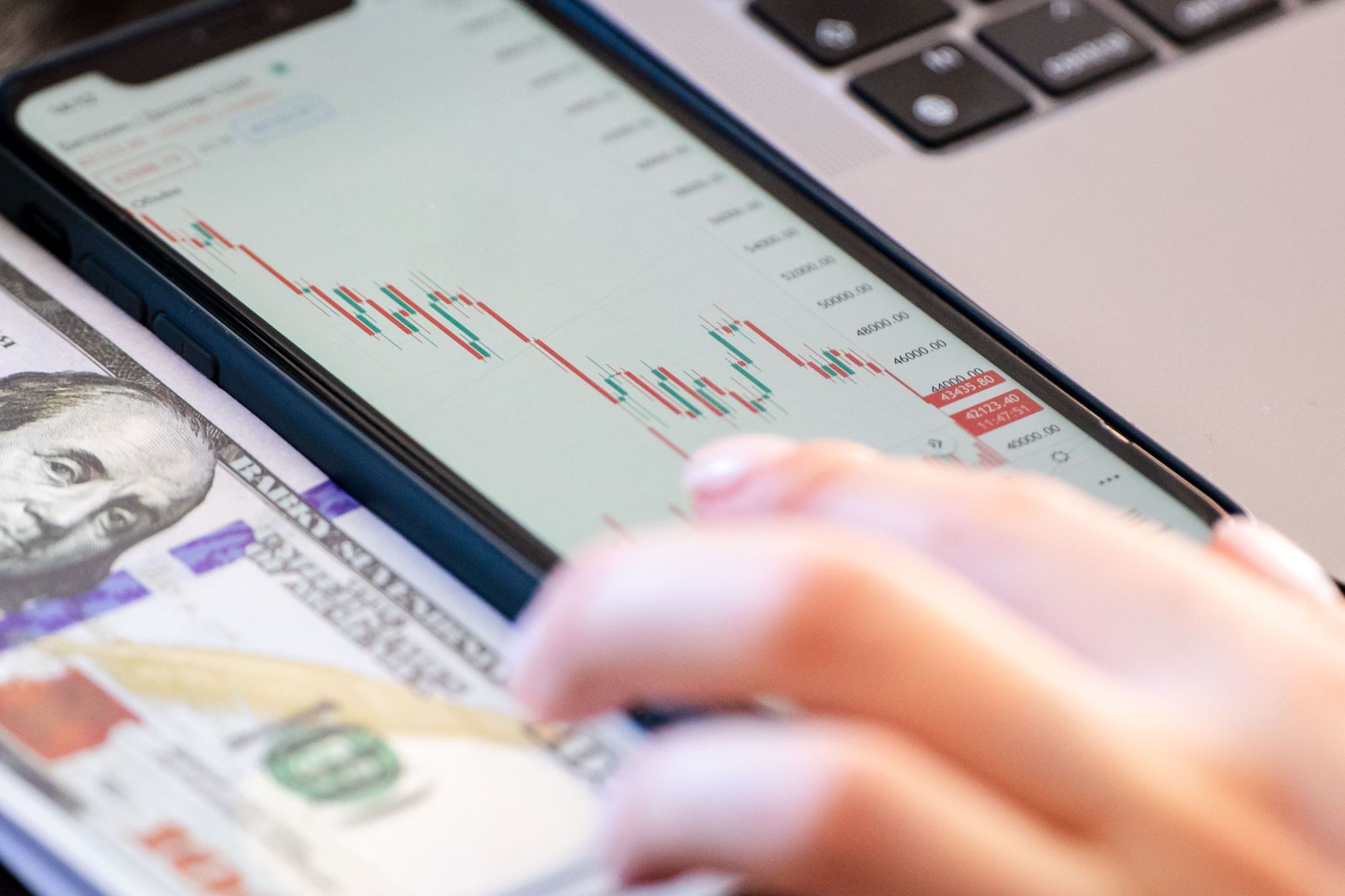 Close-up of a smartphone displaying stock market data over a dollar bill on a desk — UPI Study
