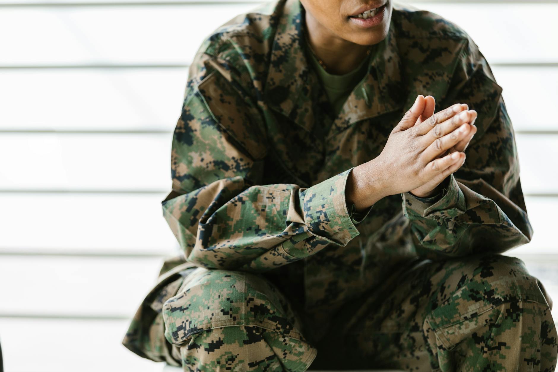 A close-up view of a soldier sitting in a camouflage uniform with clasped hands — UPI Study