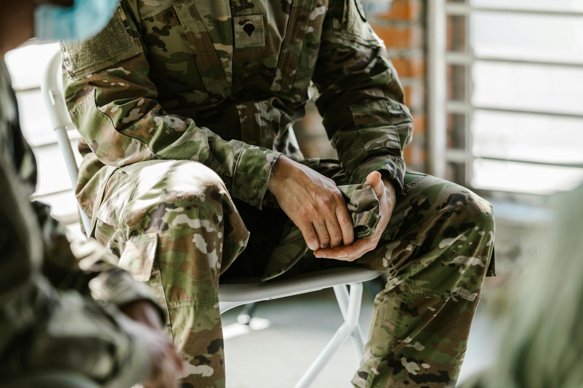 A soldier in camouflage uniform sitting indoors, representing military life and service — UPI Study