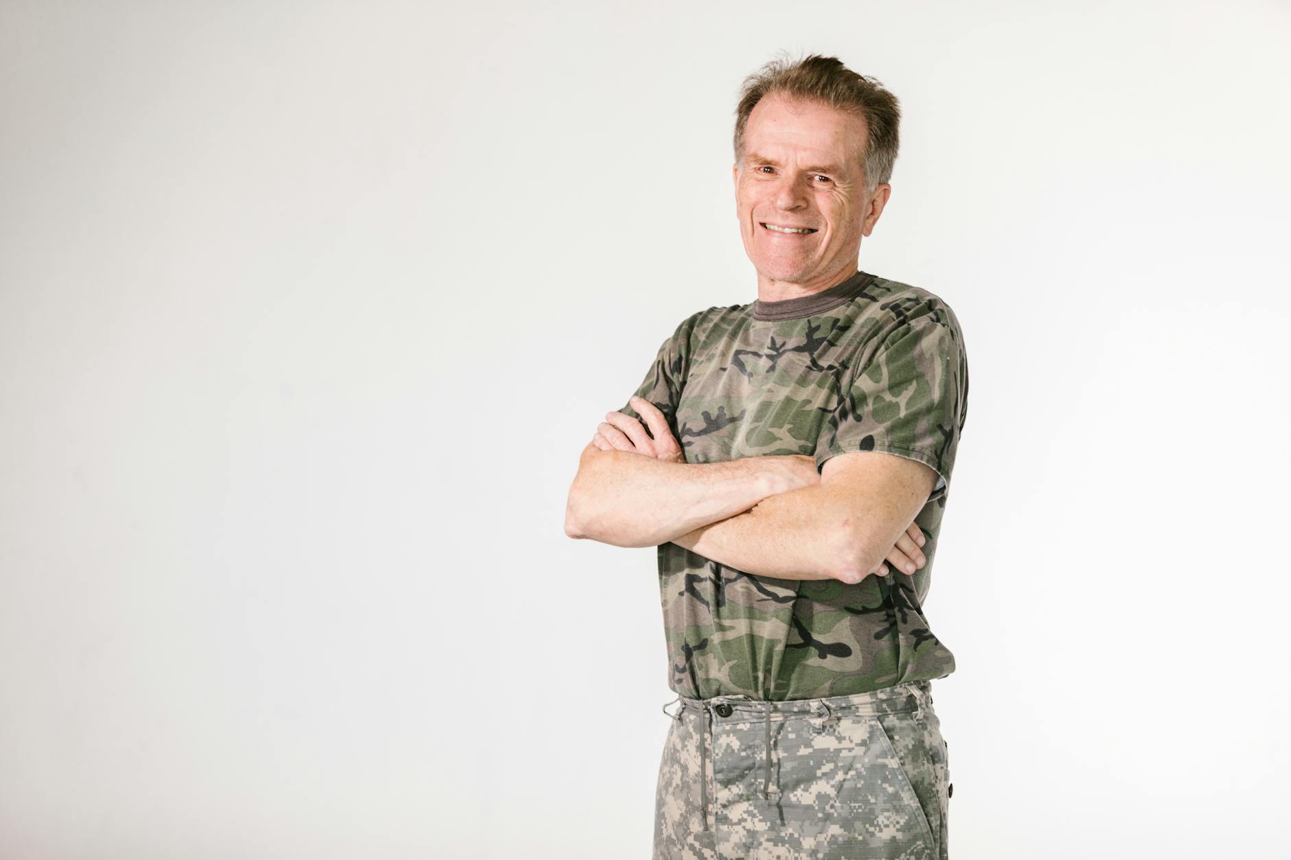 Smiling military veteran confidently posing in camouflage against a white background — UPI Study