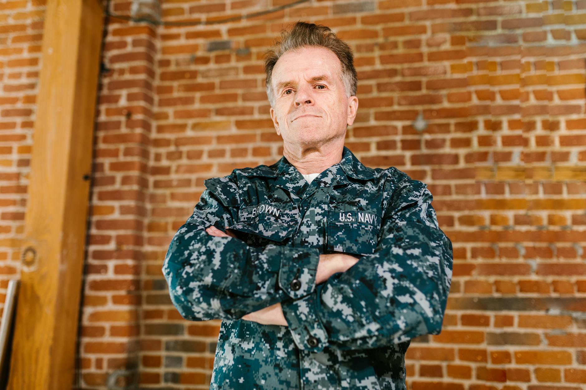 Proud US Navy veteran standing confidently in military uniform with brick background — UPI Study