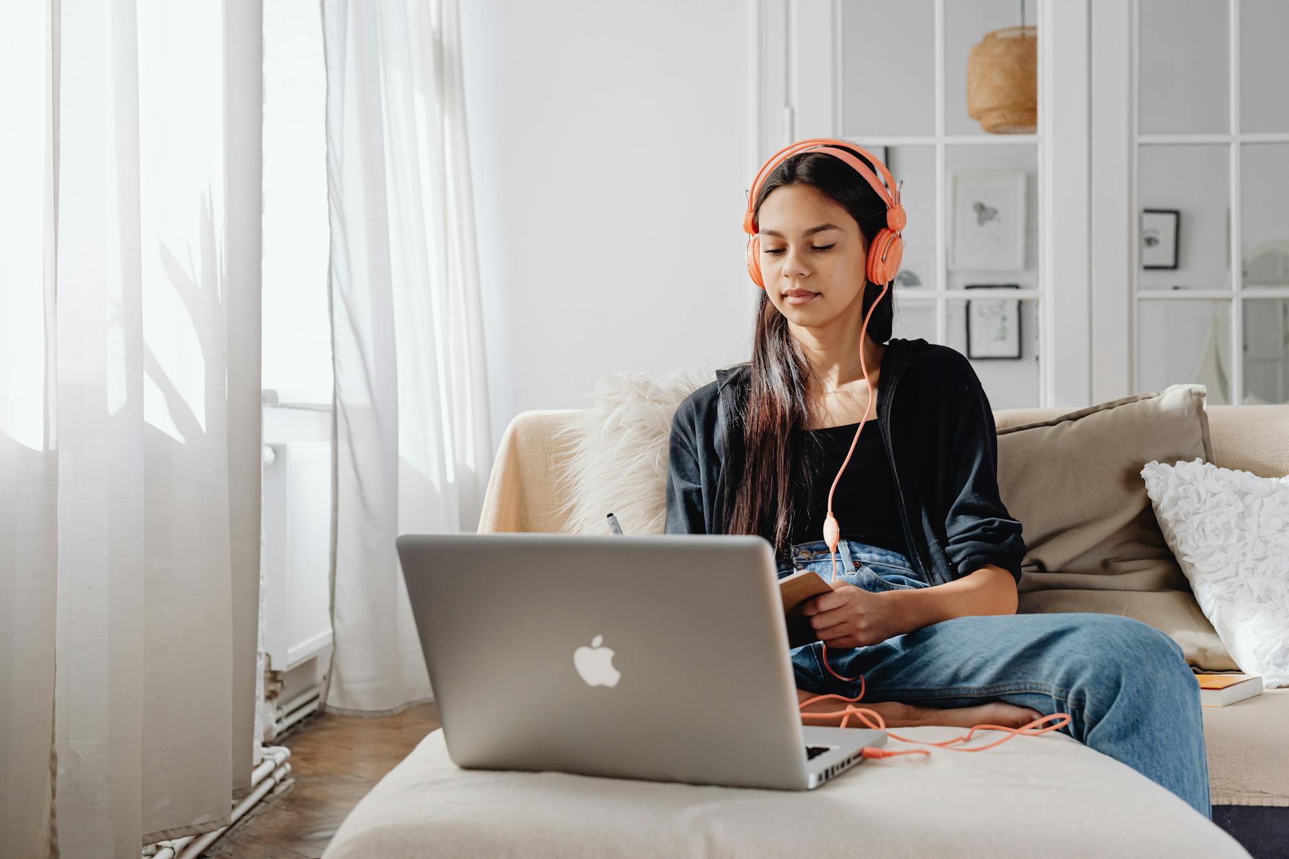 Teenage girl wearing headphones using a laptop for online learning at home in a cozy setting — UPI Study