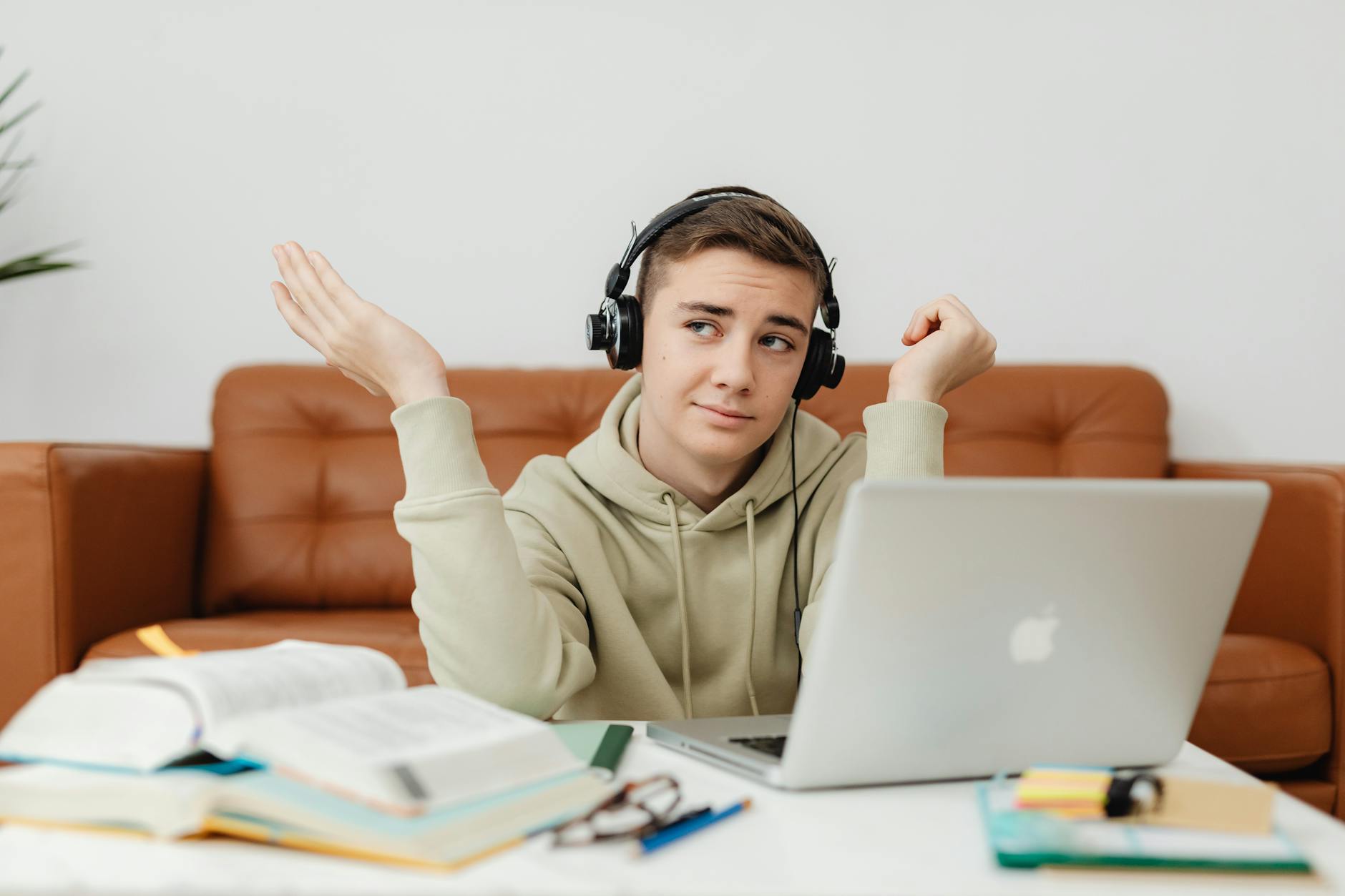 Young man in hoodie using laptop and headphones for online learning at home — UPI Study
