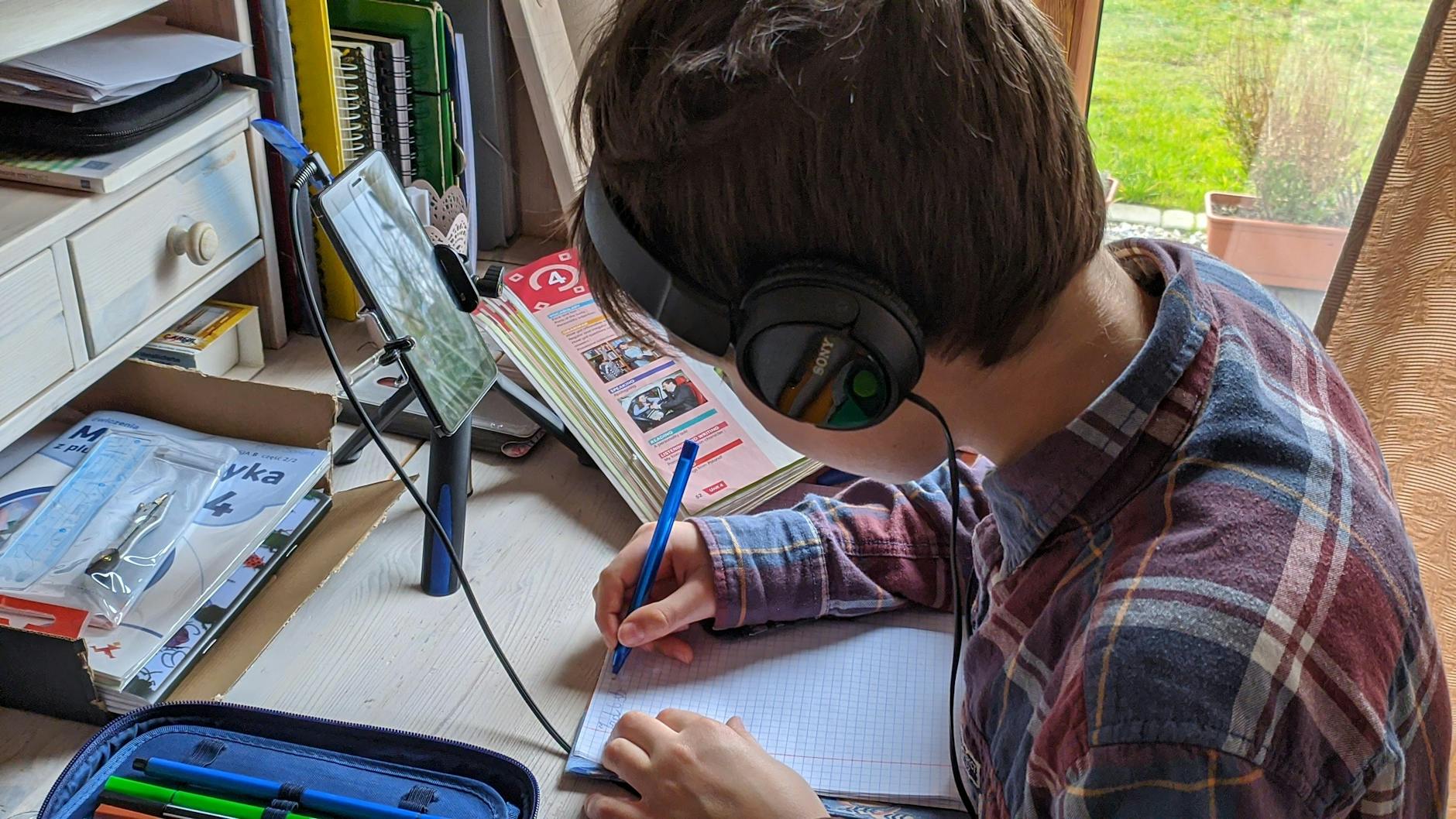 Young boy writing notes during an online class at home, focused on studying — UPI Study