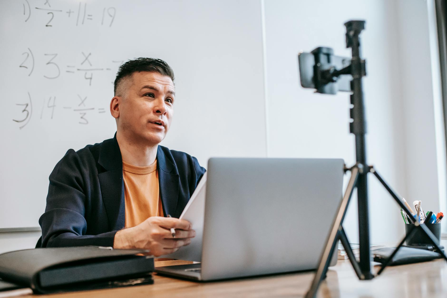 Male instructor conducting an online education session with a laptop and camera — UPI Study
