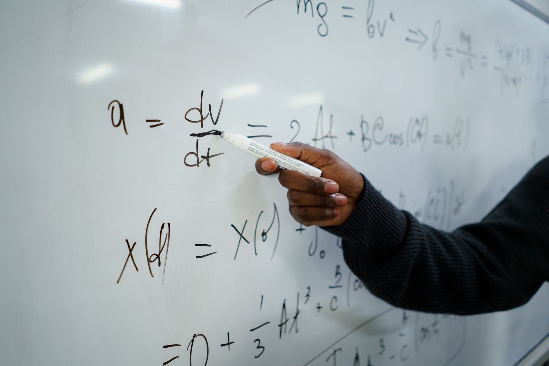 Close-up of hand writing equations on a whiteboard in a classroom setting — UPI Study