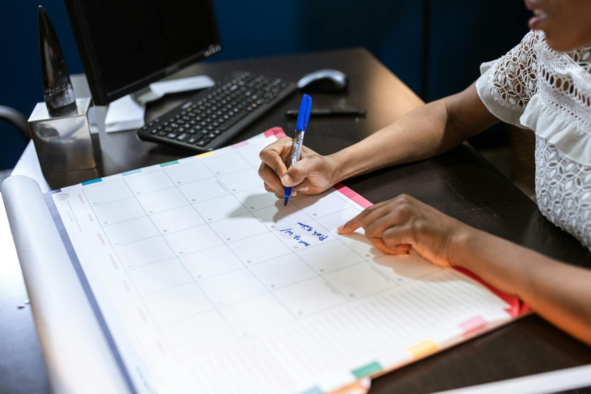 Person writing important notes in a desk calendar with a pen, set in an office — UPI Study