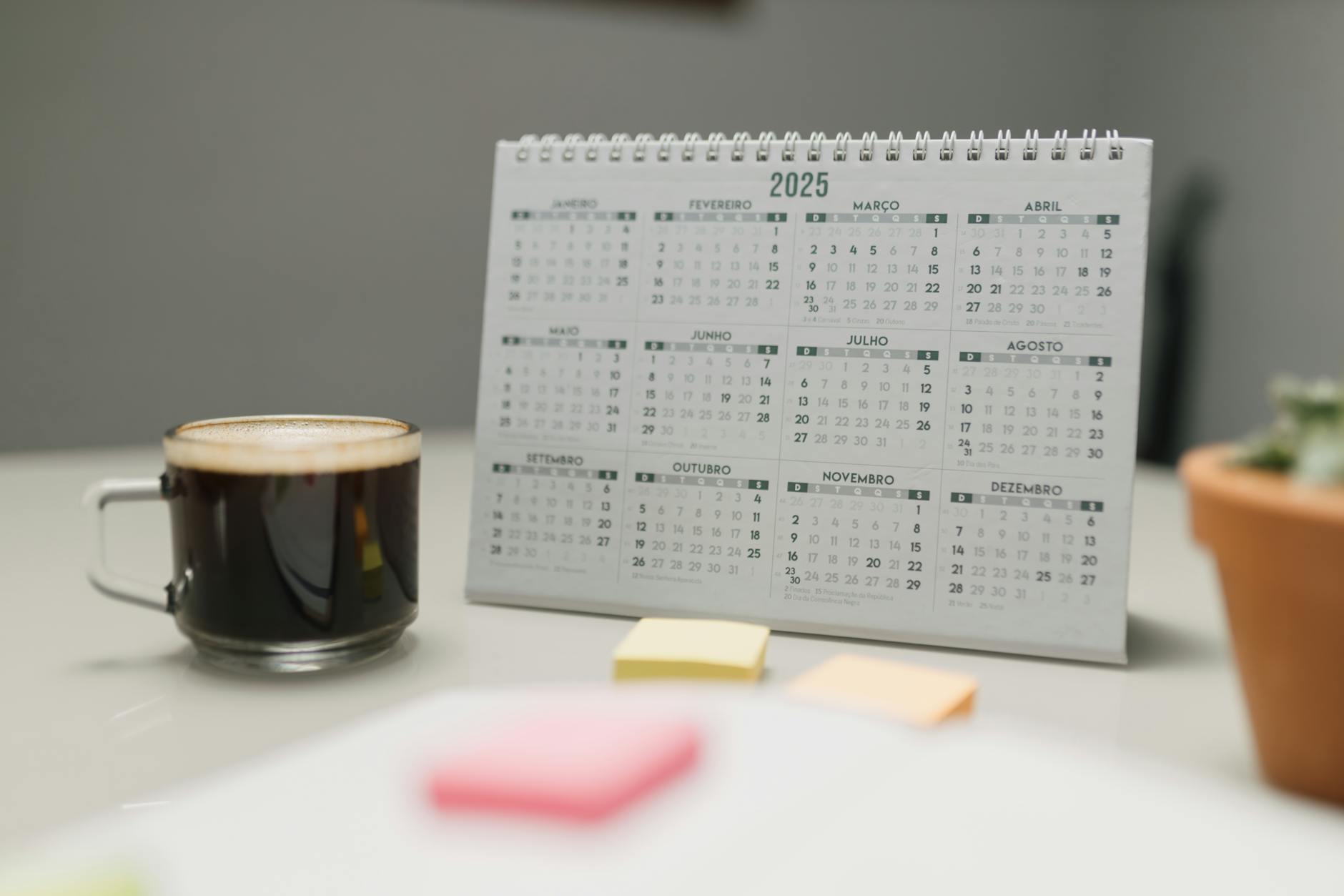 A 2025 calendar on a desk with coffee, sticky notes, and a plant in an office setting — UPI Study