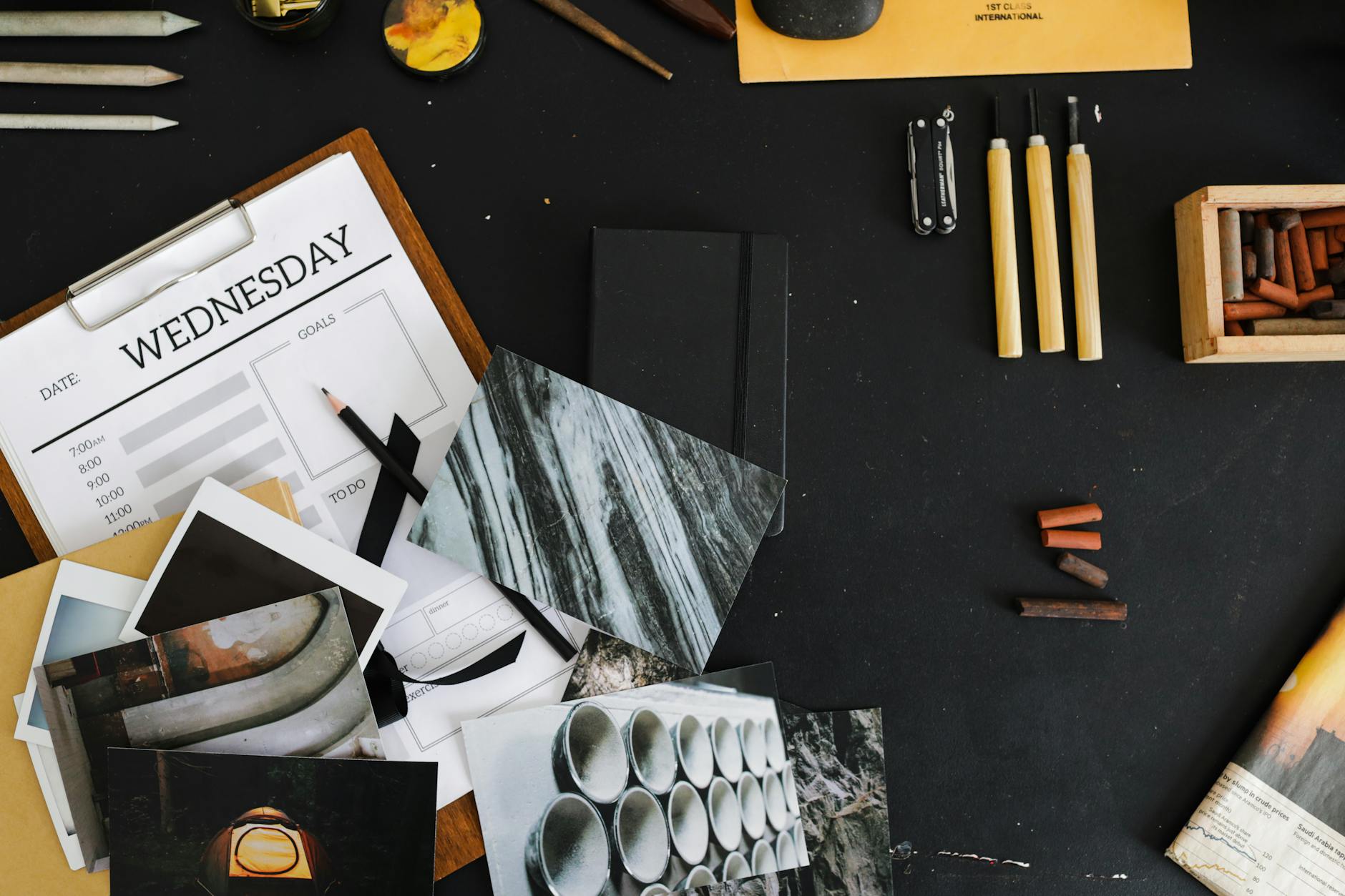 An overhead view of a creative workspace with art supplies, photographs, and a weekly planner — UPI Study