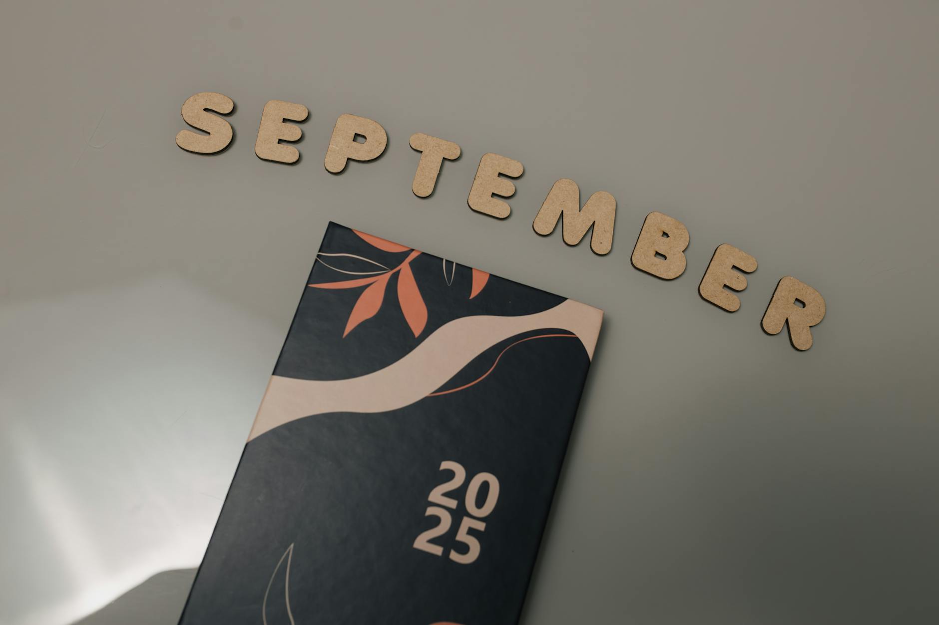 Flat lay of a 2025 calendar with September in wooden letters and an autumn design on a neutral background — UPI Study