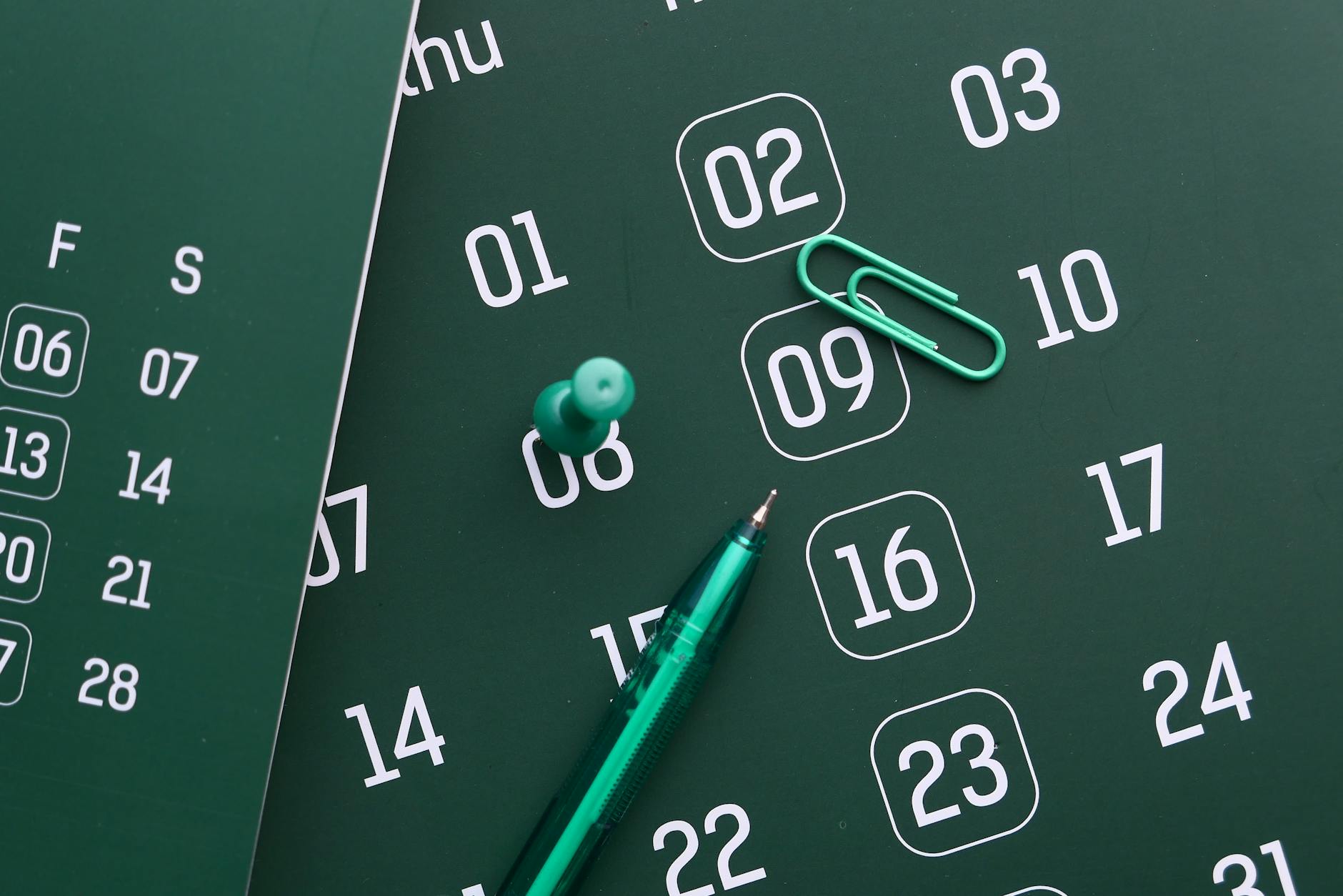 Close-up of a green calendar with pen, push pin, and paper clip for planning and organization — UPI Study