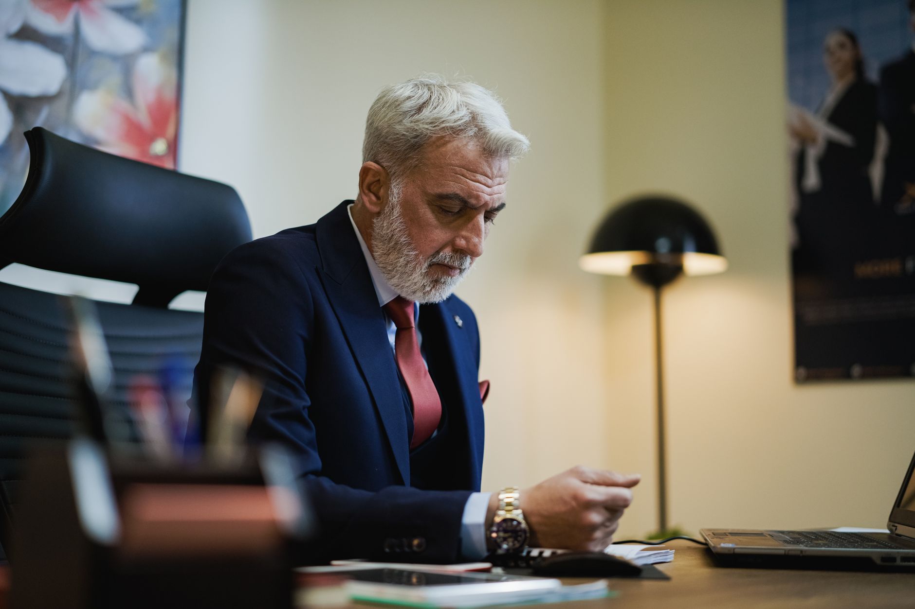 Senior businessman in formal attire working at his office desk with focused expression — UPI Study