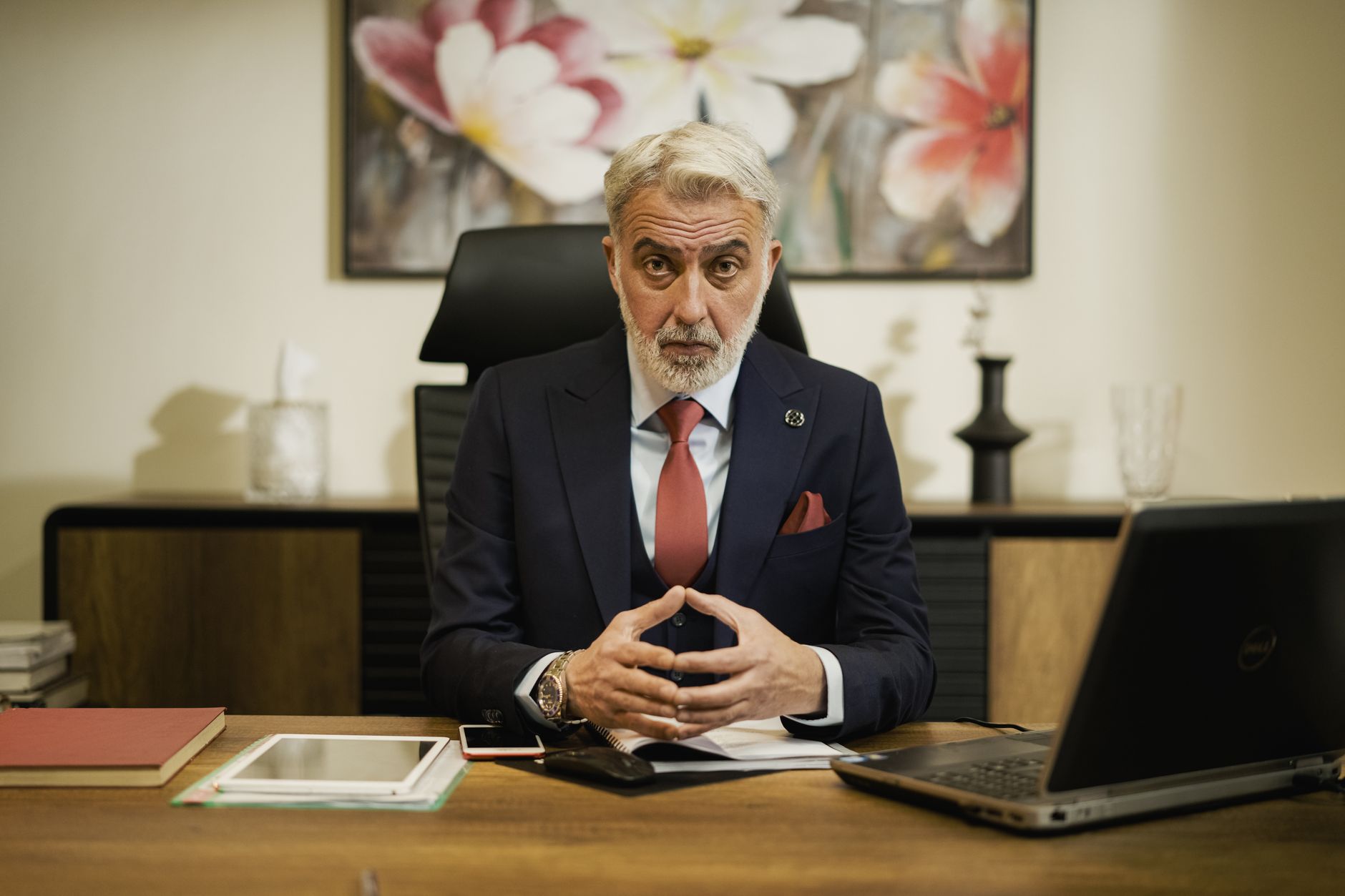 Professional middle-aged businessman sitting confidently at his executive desk in an office setting — UPI Study