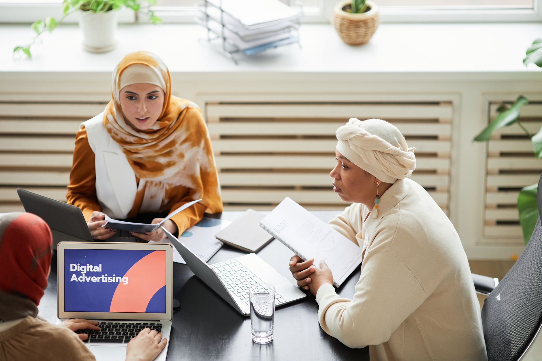Three women in hijabs collaborating on digital advertising strategies around a table with laptops — UPI Study