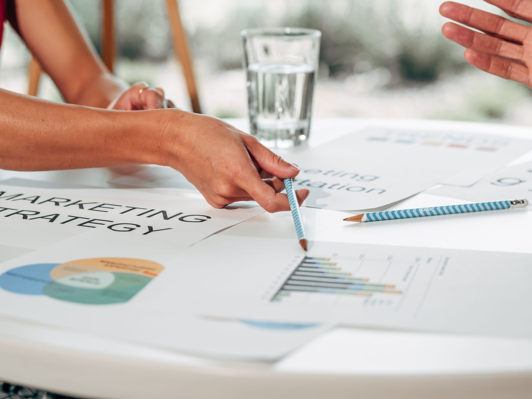 Hands discussing marketing strategy with charts in an office setting — UPI Study
