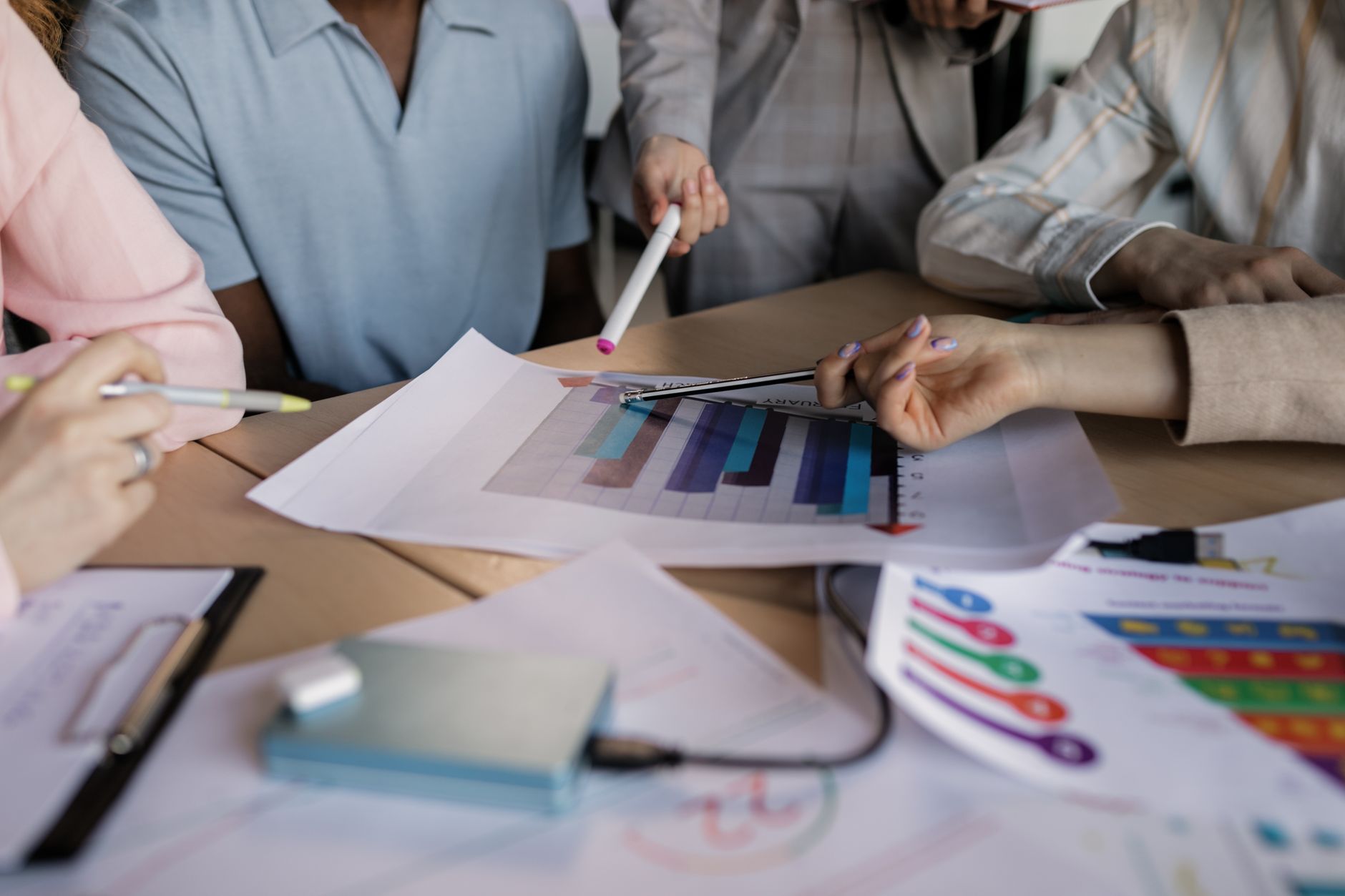A diverse team engaged in planning and discussing a business strategy around a wooden table indoors — UPI Study
