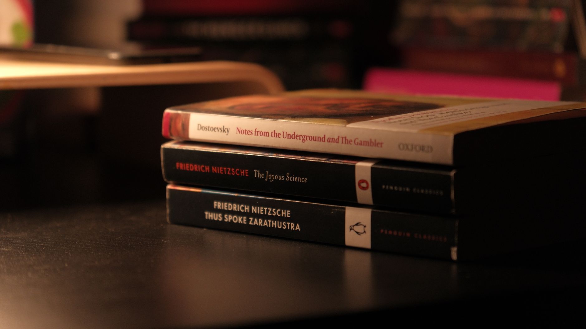 Stack of classic books by Dostoevsky and Nietzsche on a dark desk — UPI Study
