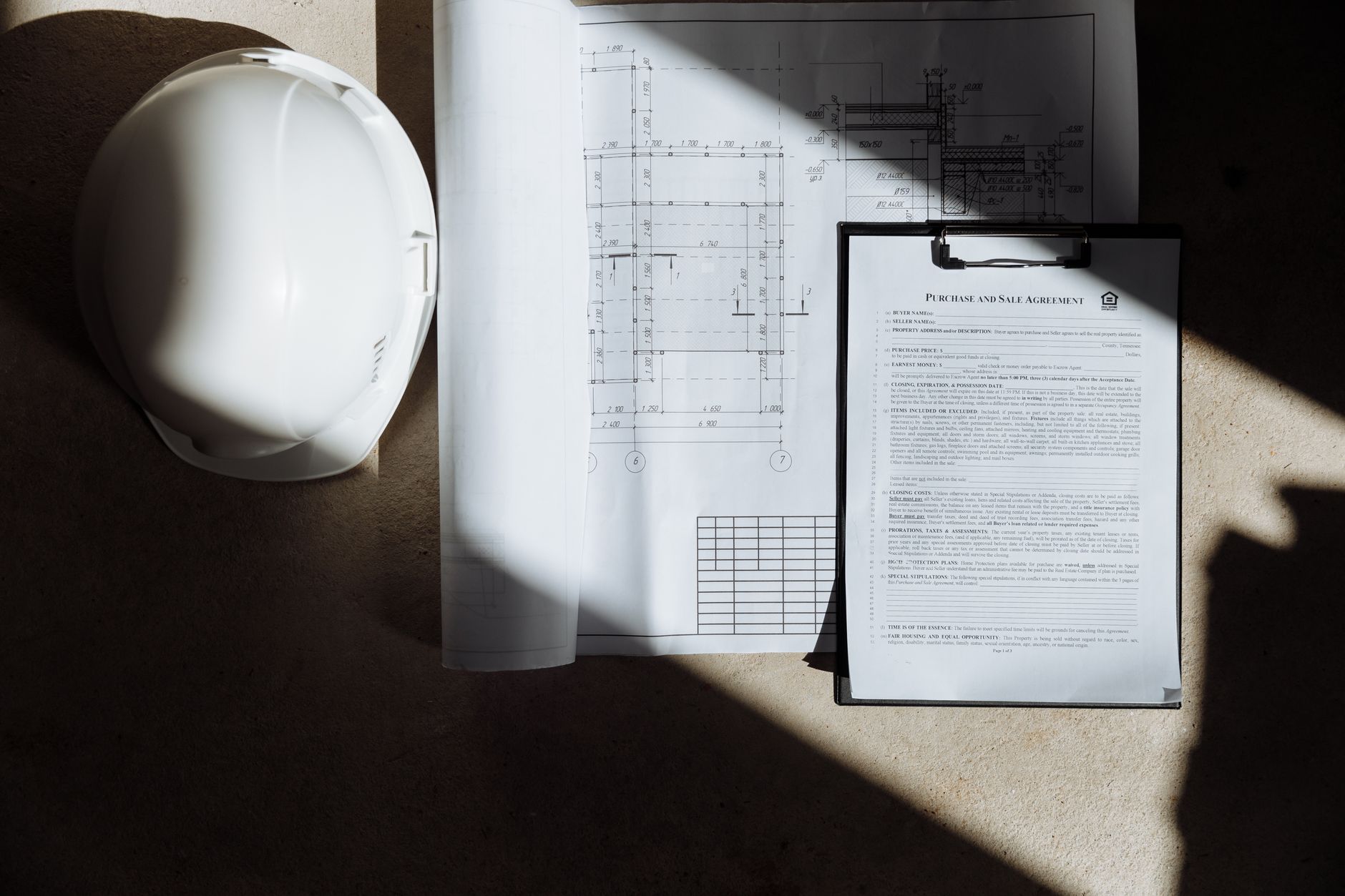 Top view of construction documents and hard hat in sunlight, capturing planning essence — UPI Study