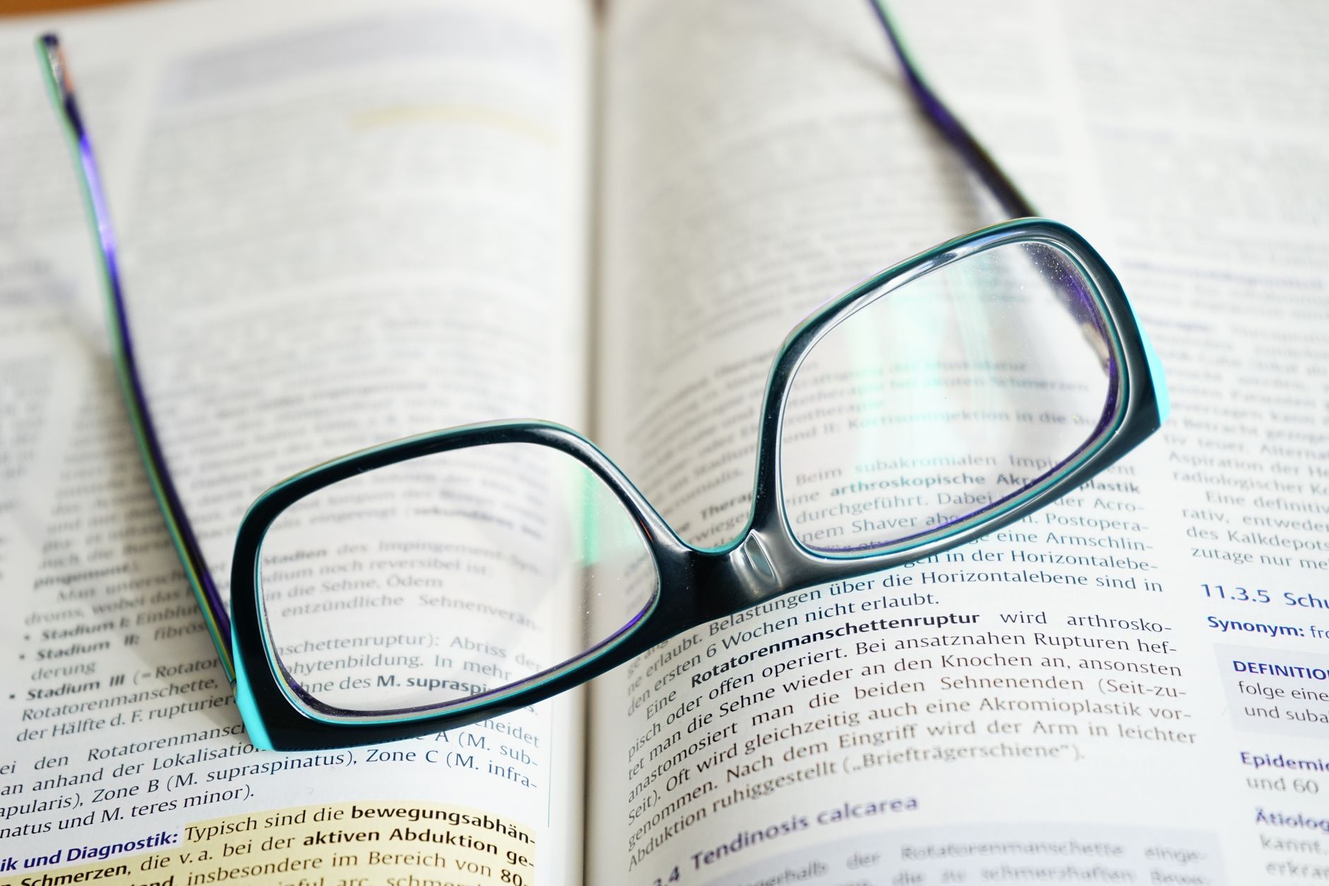 Reading glasses resting on an open textbook, symbolizing study and knowledge — UPI Study