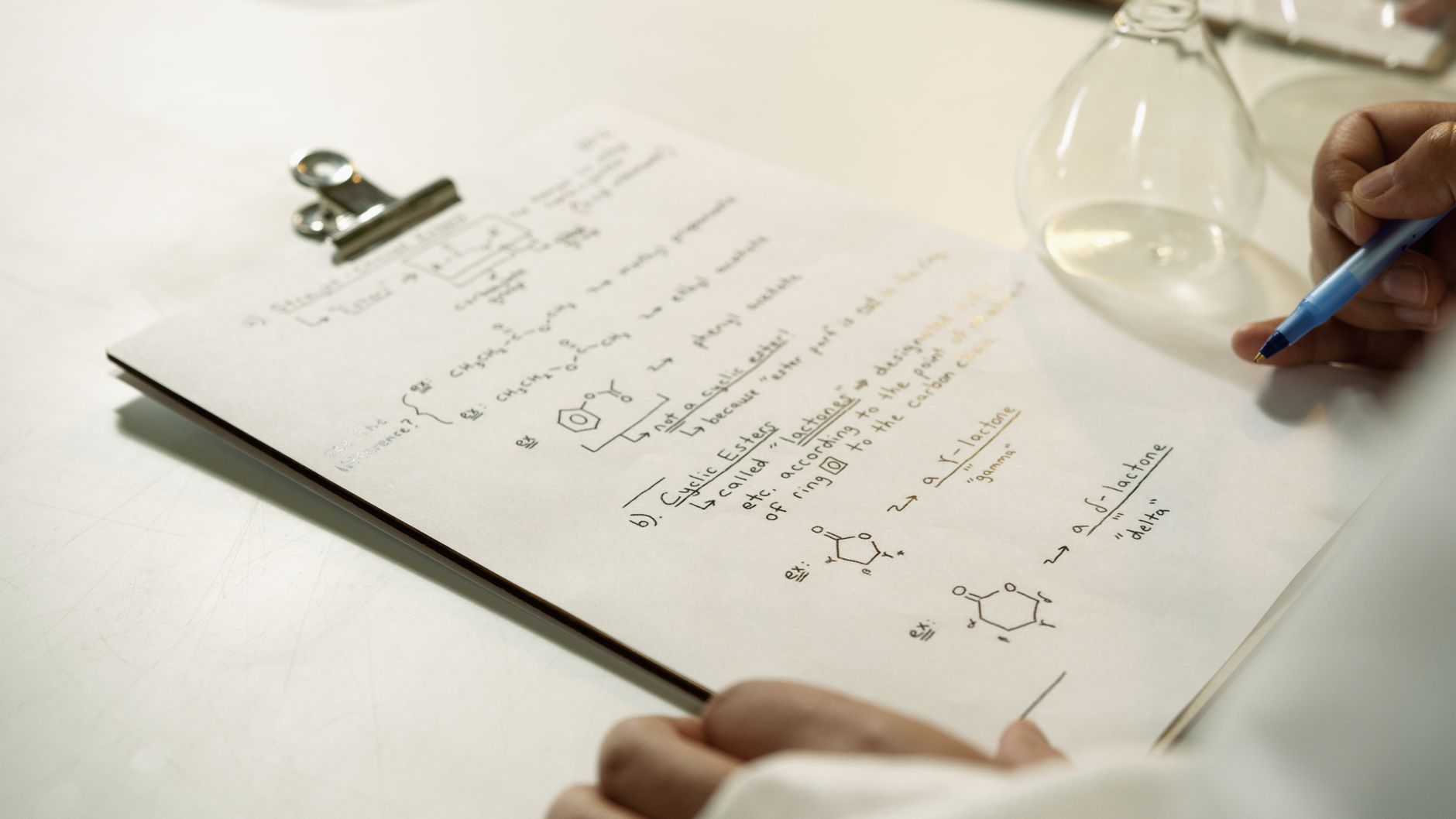 A close-up view of handwritten chemical formulas on a clipboard in a lab setting — UPI Study