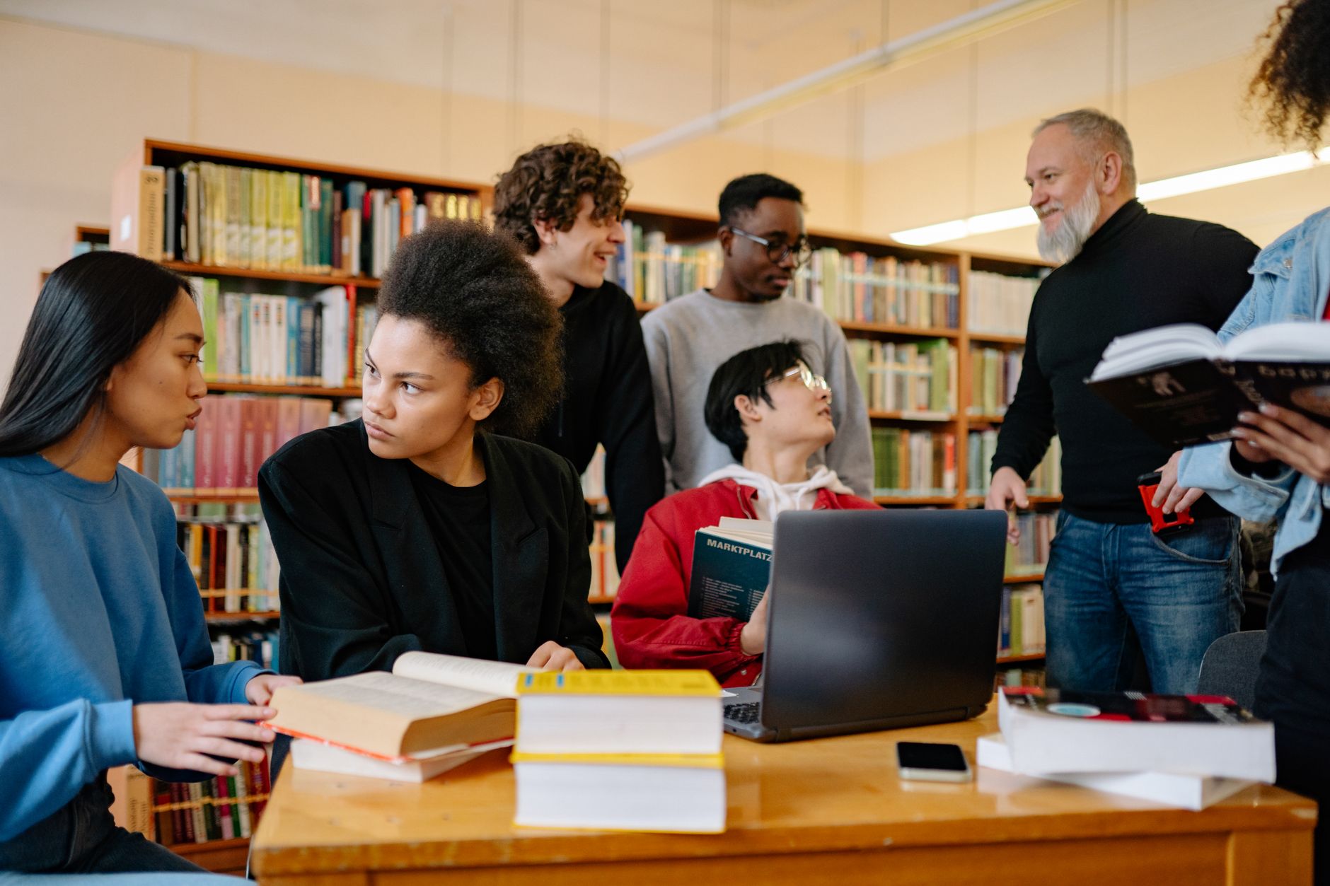 A diverse group of students studying together at a university library, engaged in discussion — UPI Study