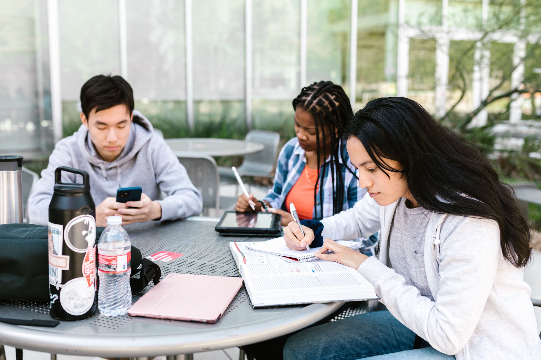 Group of students studying together outside, using books and technology — UPI Study