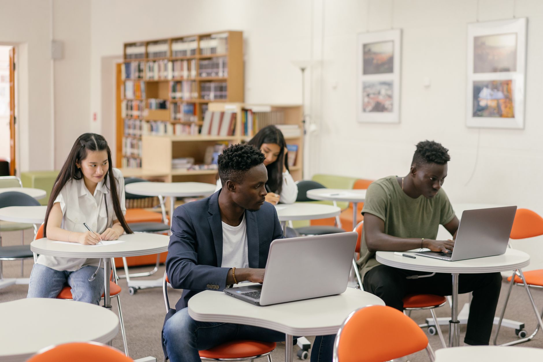 Students focused on laptops and notes in a bright classroom setting — UPI Study