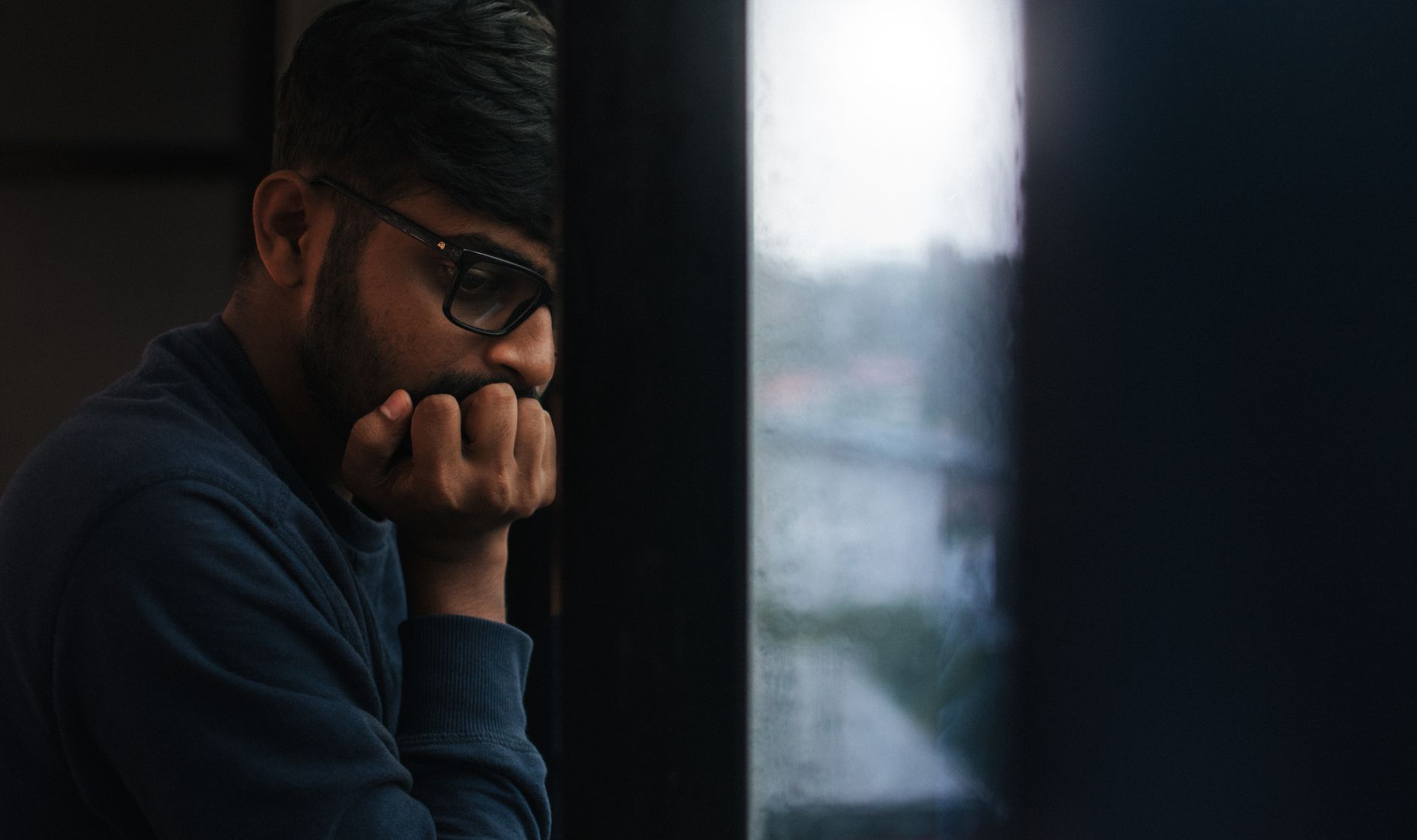 Contemplative man gazing out a rainy window, lost in thought — UPI Study