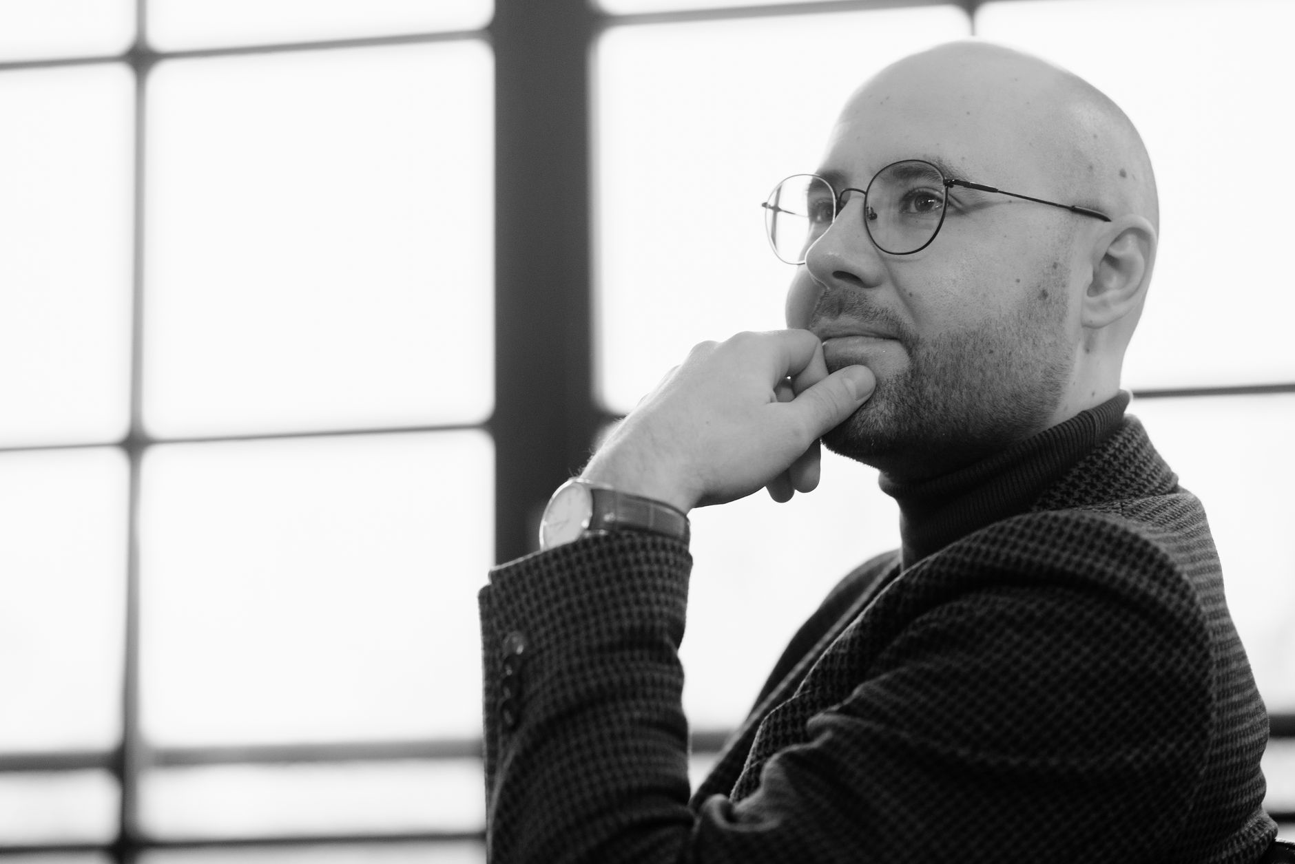 Bald man in glasses deep in thought, captured in monochrome indoor setting — UPI Study