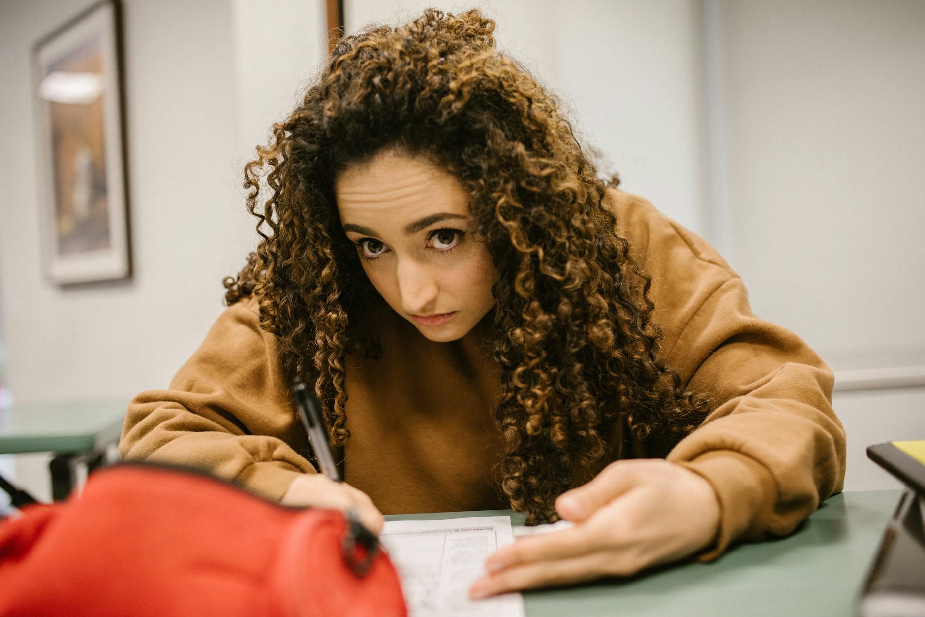 Female student deeply engaged in exam writing in a classroom setting — UPI Study