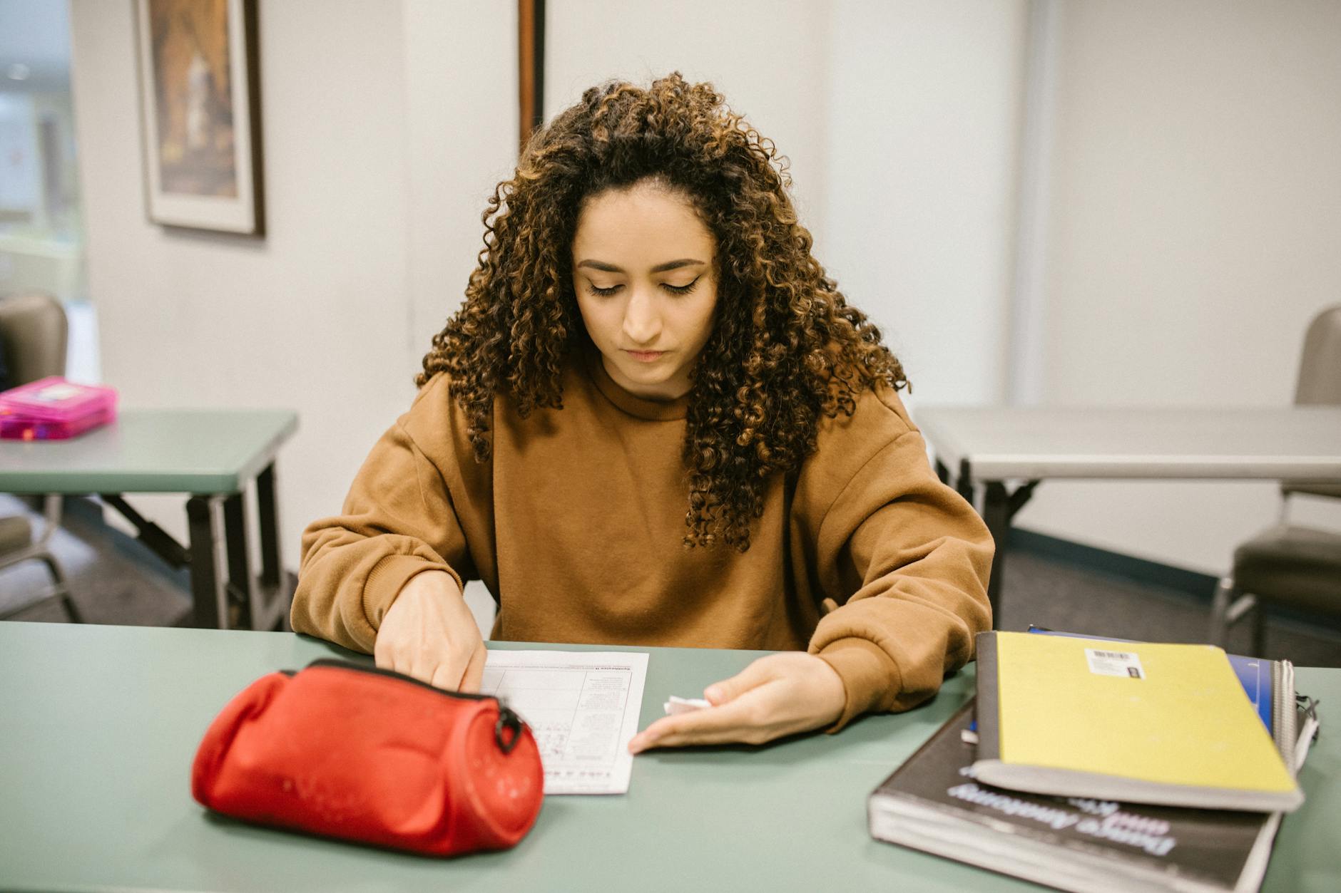 Young woman studying for an exam in a college classroom with books and notes — UPI Study