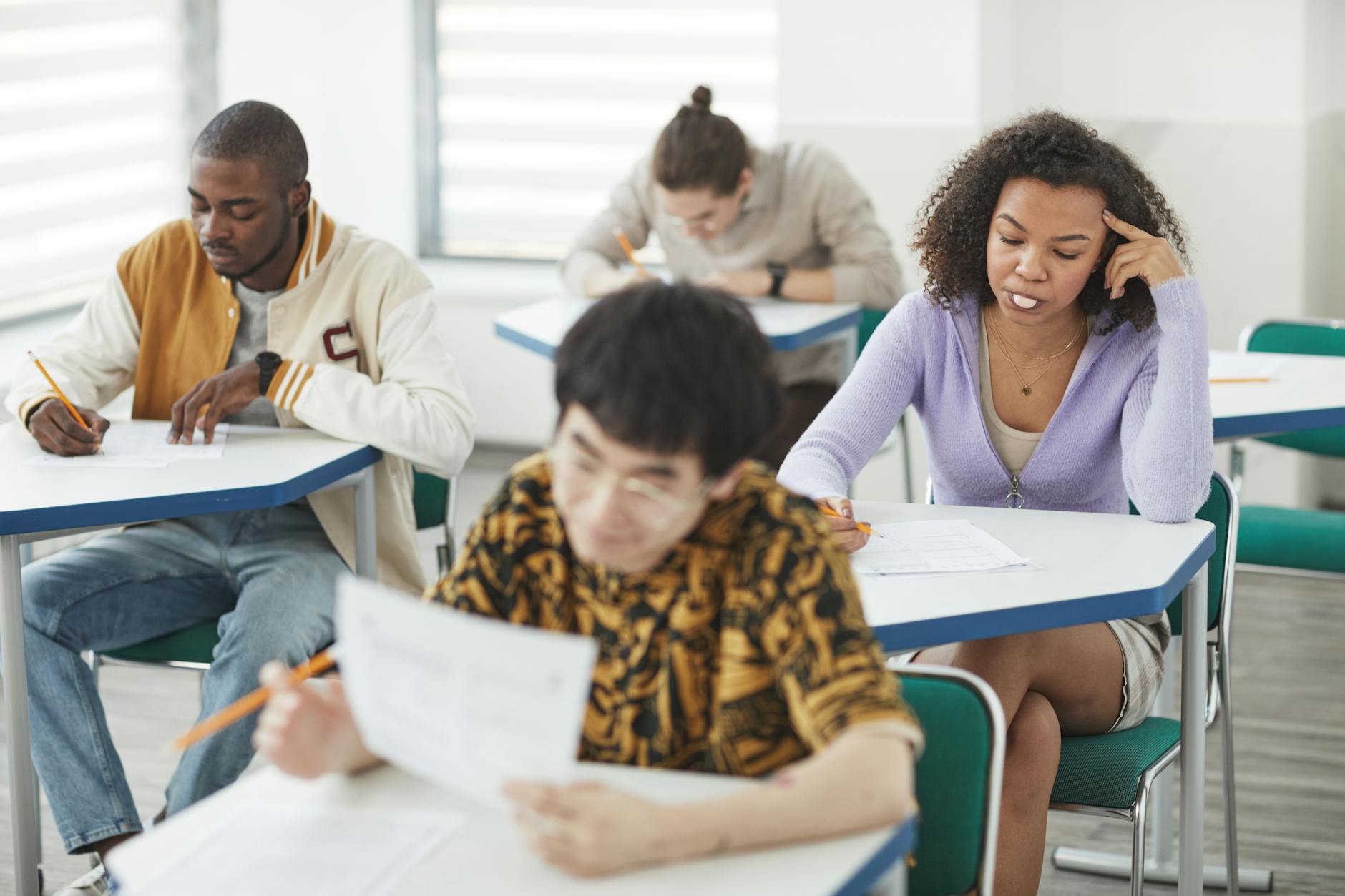 Students of various backgrounds focused on an exam in a bright, modern classroom setting — UPI Study