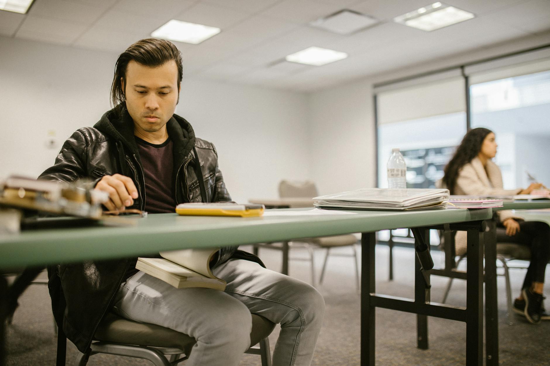 Two college students engaged in focused study at a classroom desk, preparing for exams — UPI Study