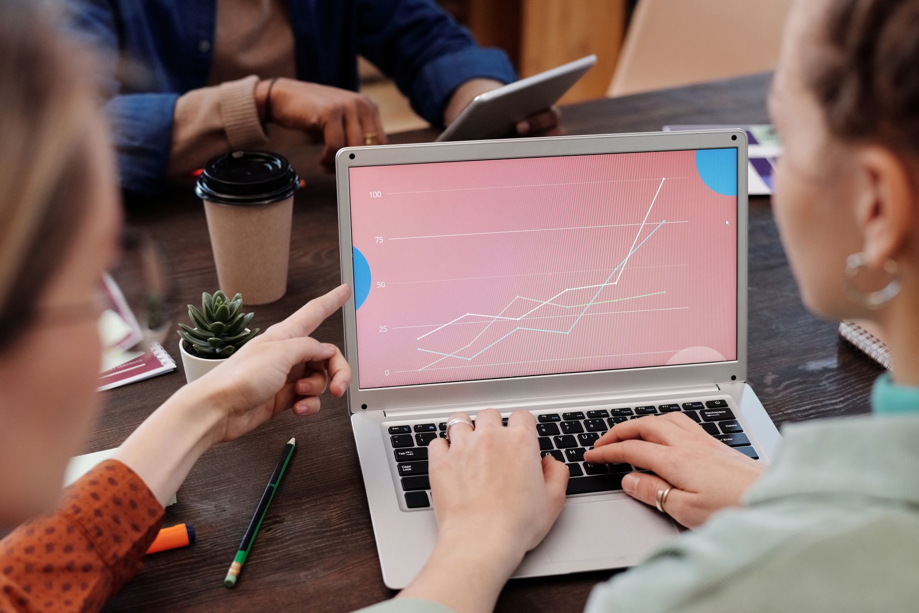Office workers collaboratively reviewing data trends on a laptop during a meeting — UPI Study