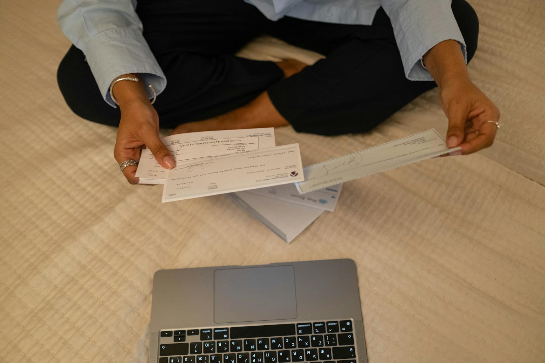 Close-up of hands holding cheques beside a laptop indoors for financial tasks — UPI Study