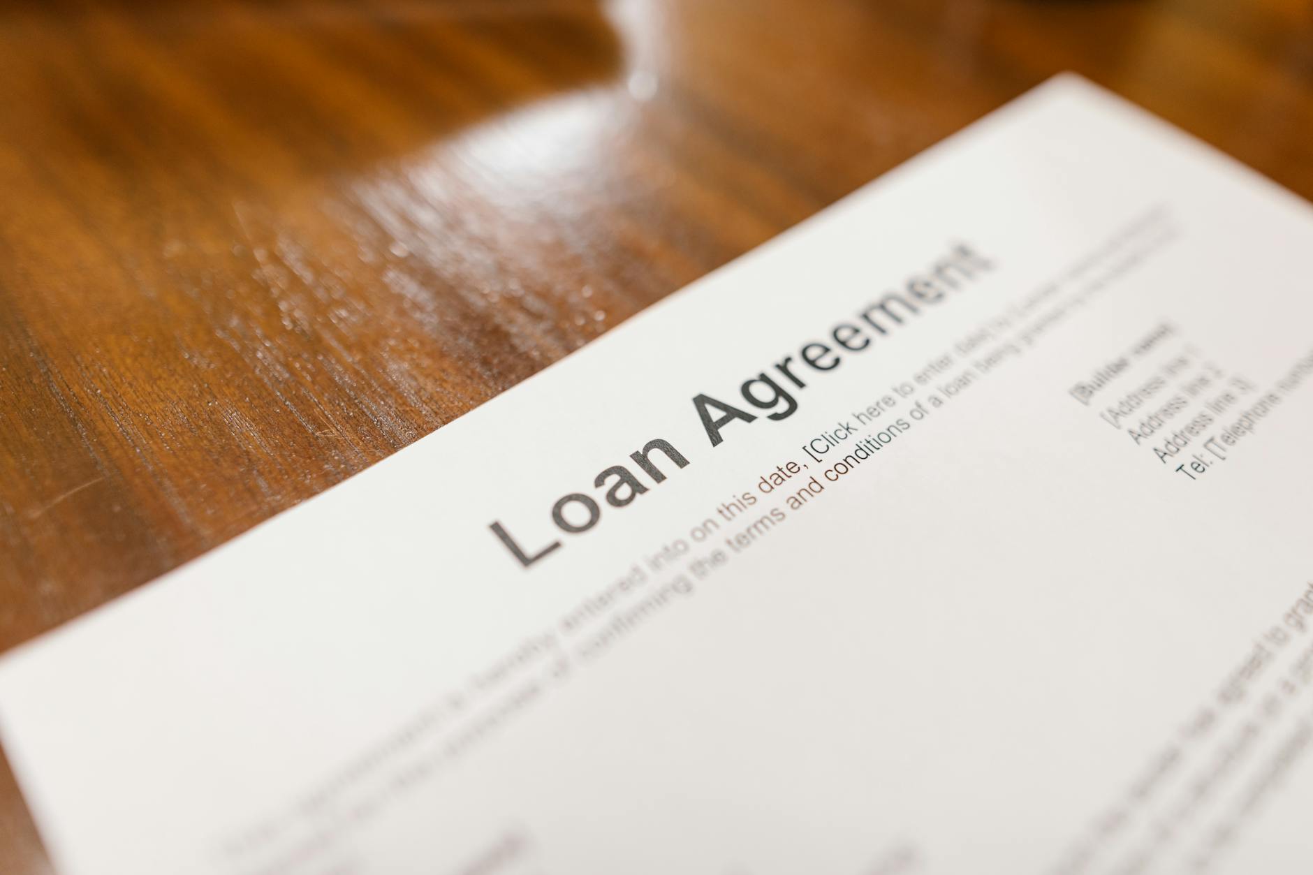 Detailed loan agreement document close-up on a wooden table representing legal and financial concepts — UPI Study