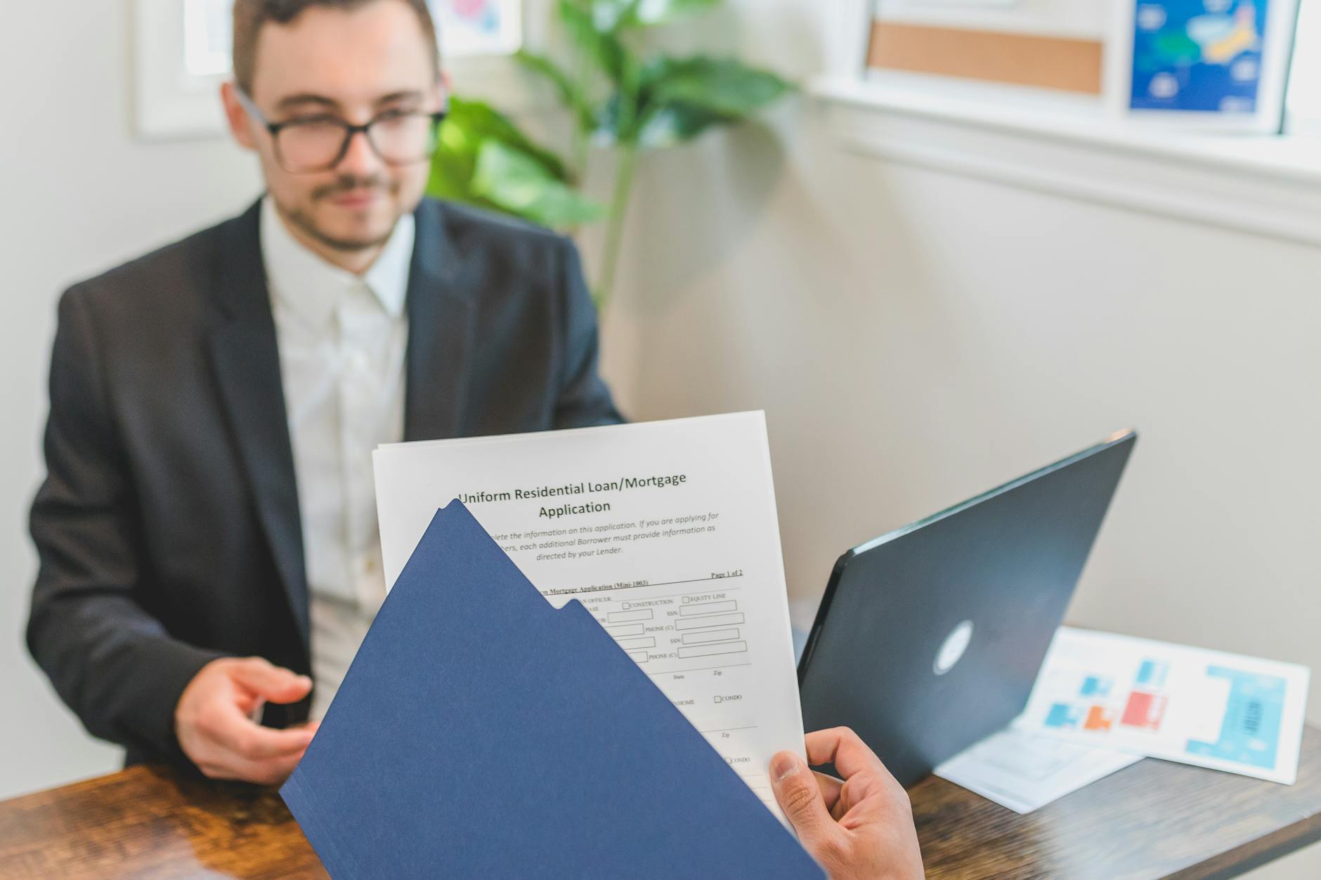 Mortgage broker and client discussing loan application with documents on table — UPI Study