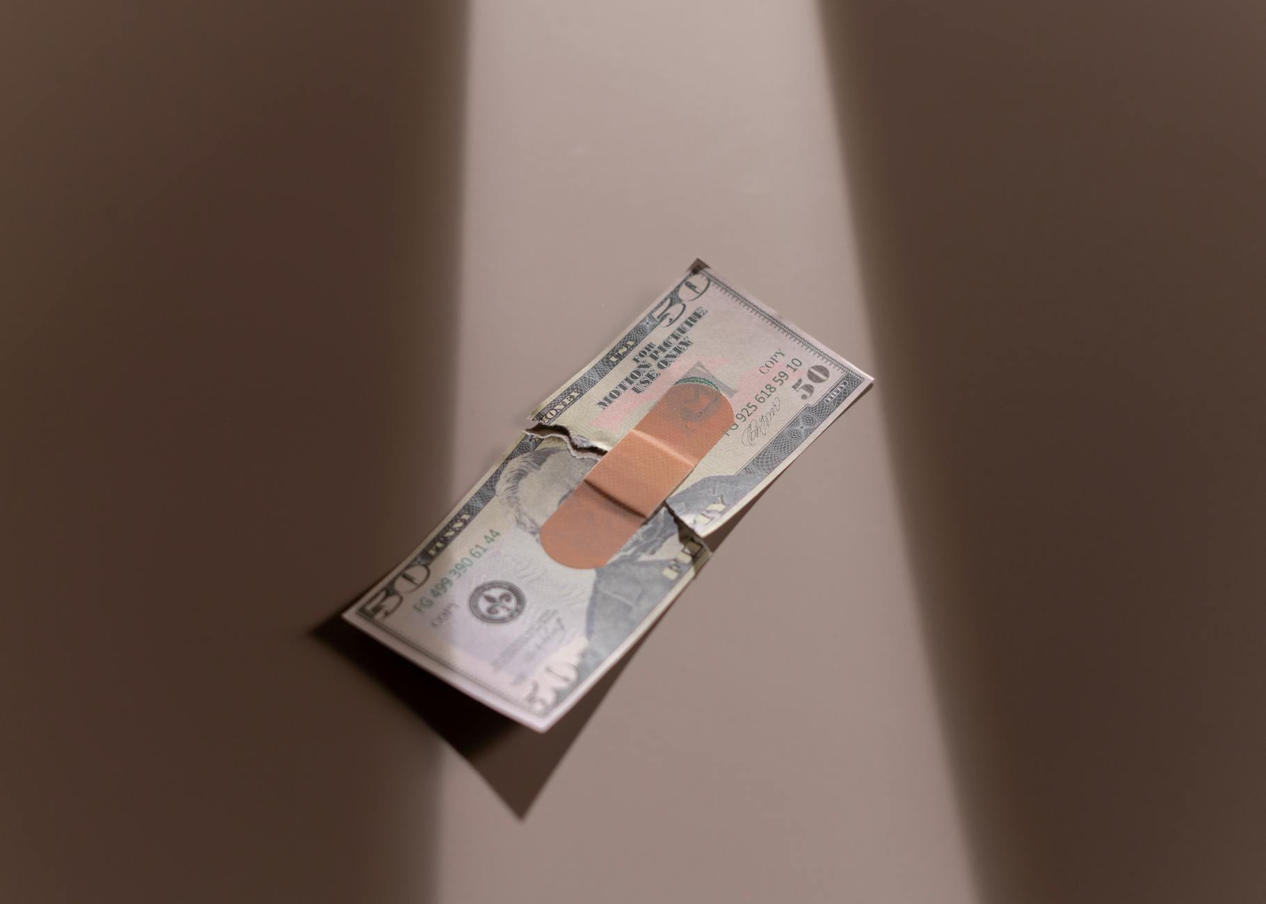 A $50 bill with a bandage symbolizes financial recovery and repair — UPI Study