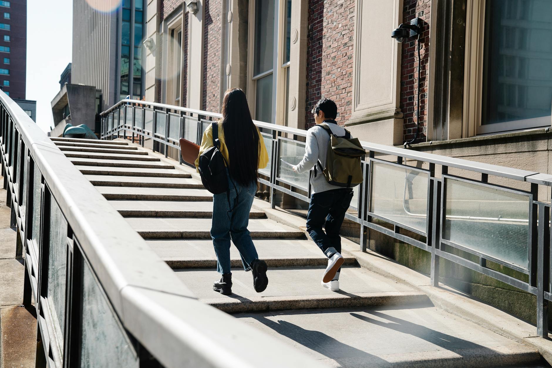 Two students walk up an outdoor staircase toward a university building — UPI Study