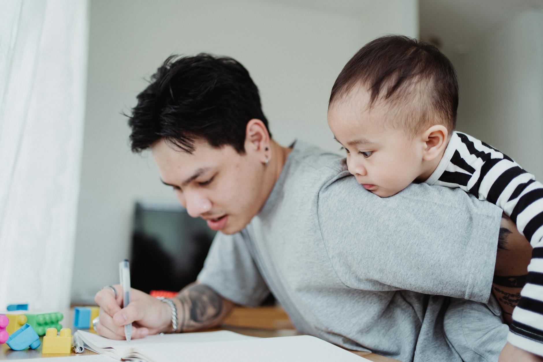 A father multitasking work while carrying his child, highlighting parenthood challenges — UPI Study