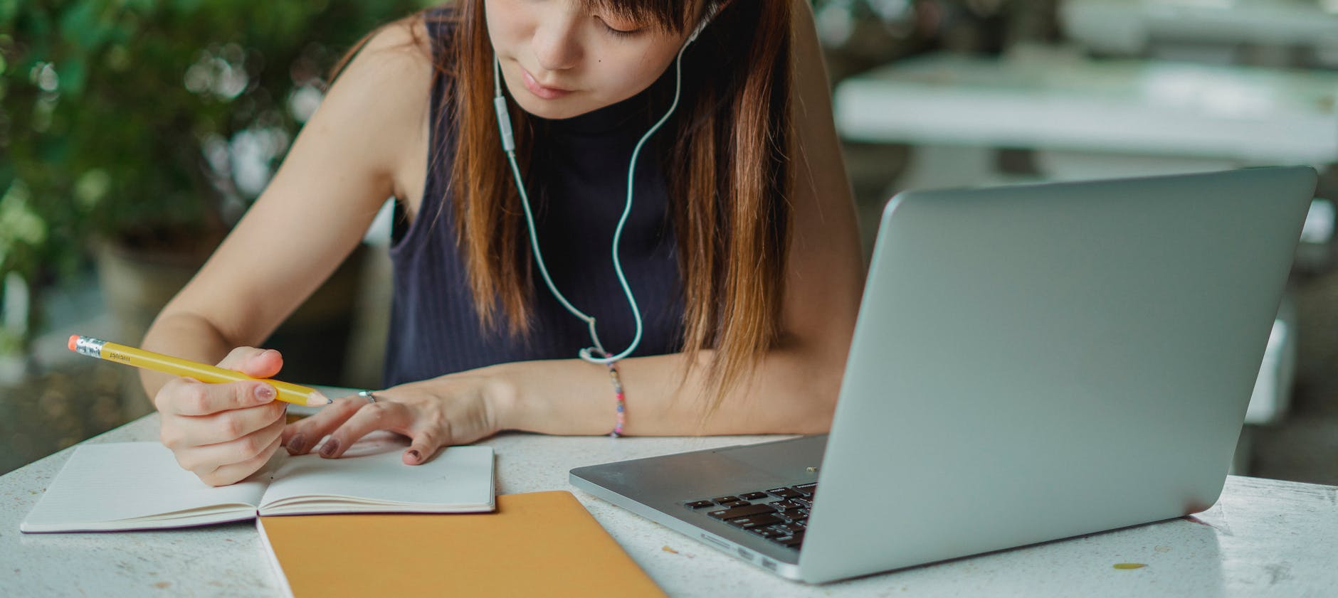 A young woman takes notes while studying with a laptop. Ideal for educational and lifestyle concepts — UPI Study